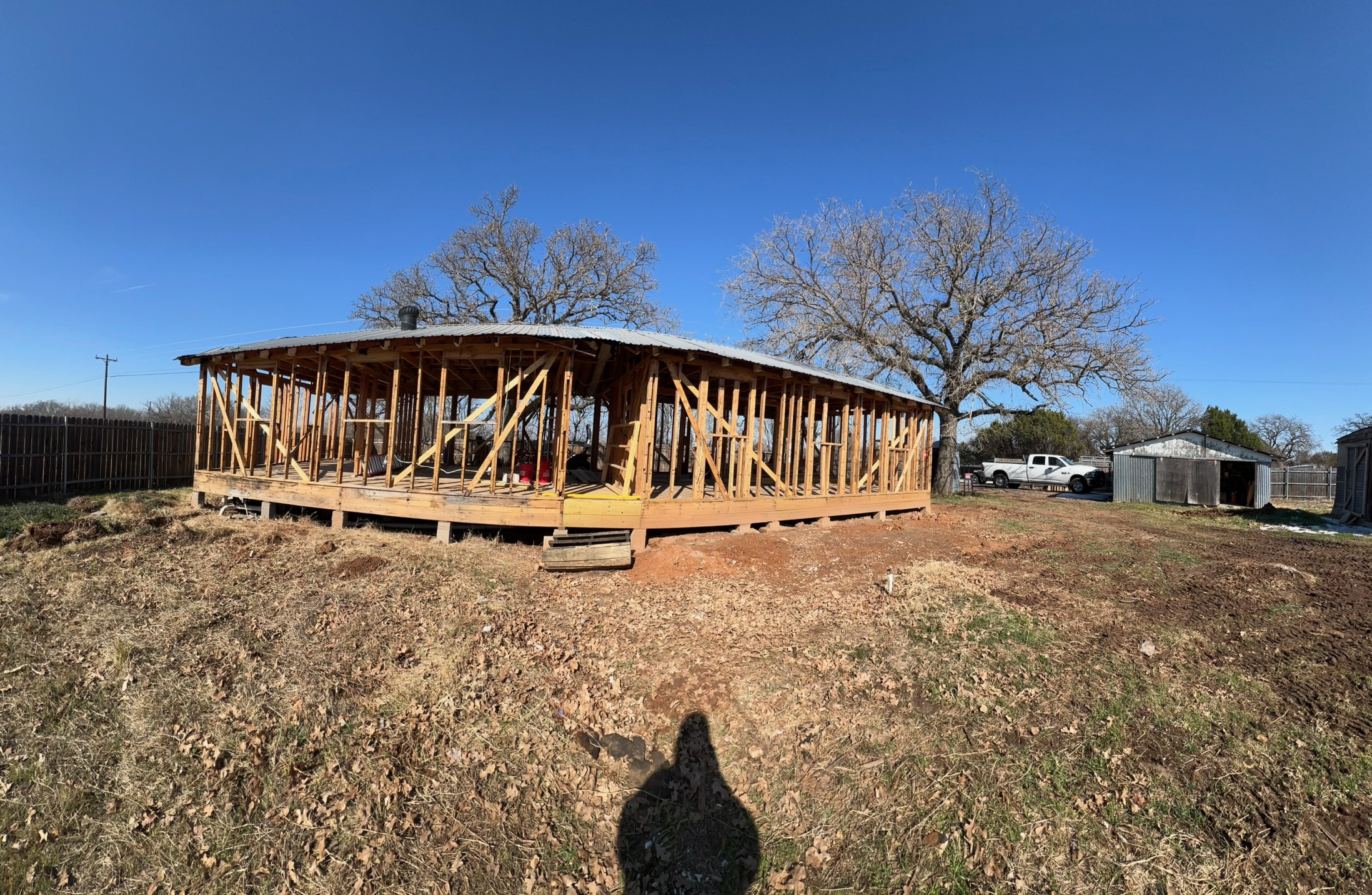 Wide view of the back of the lot with a large oak tree and open sky.